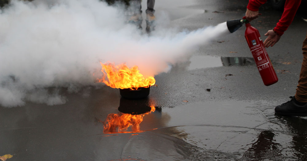 Homme éteignant un départ de feu avec un extincteur